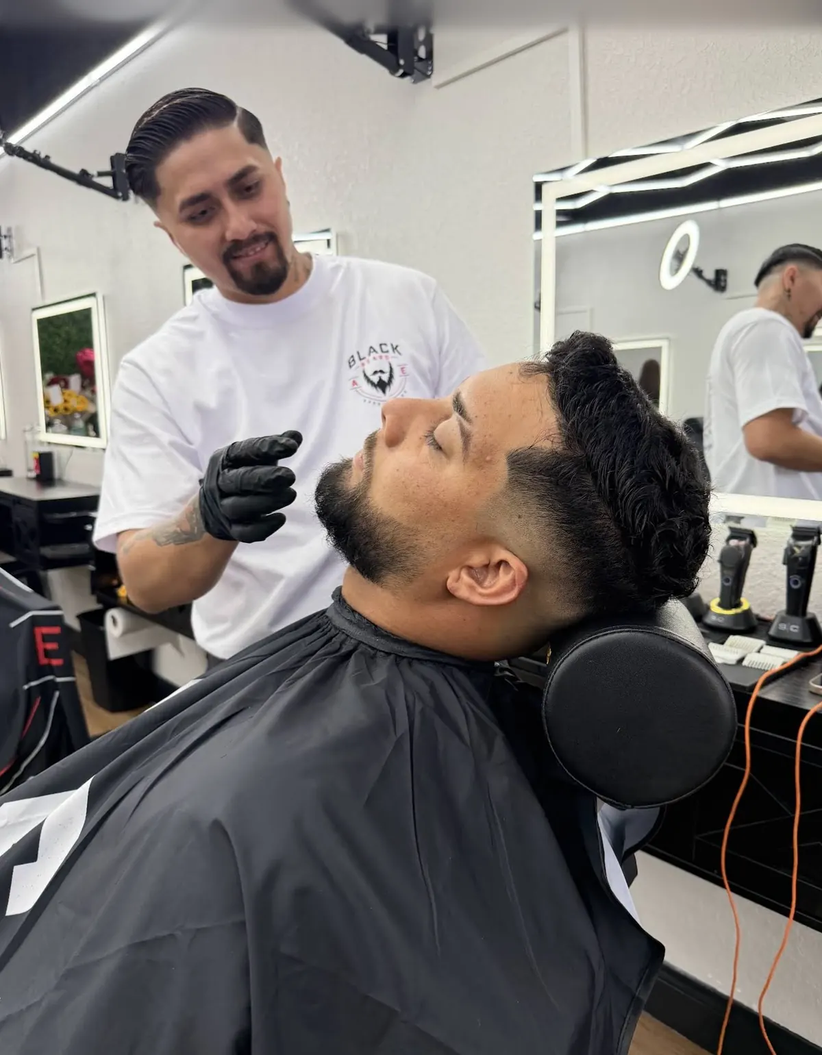 Barber grooming a client's beard in the barber chair