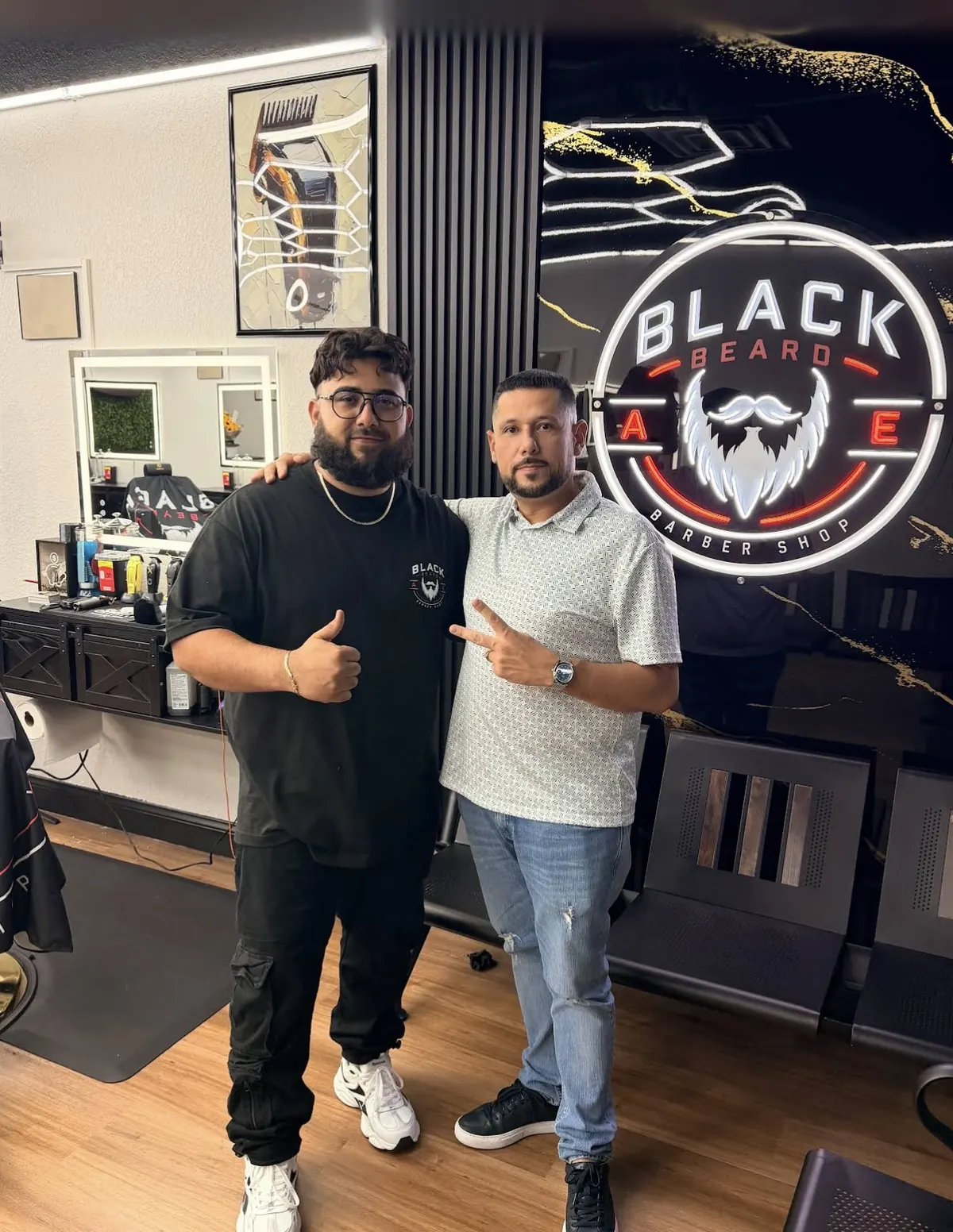 Two men posing in front of the illuminated Black Beard neon sign